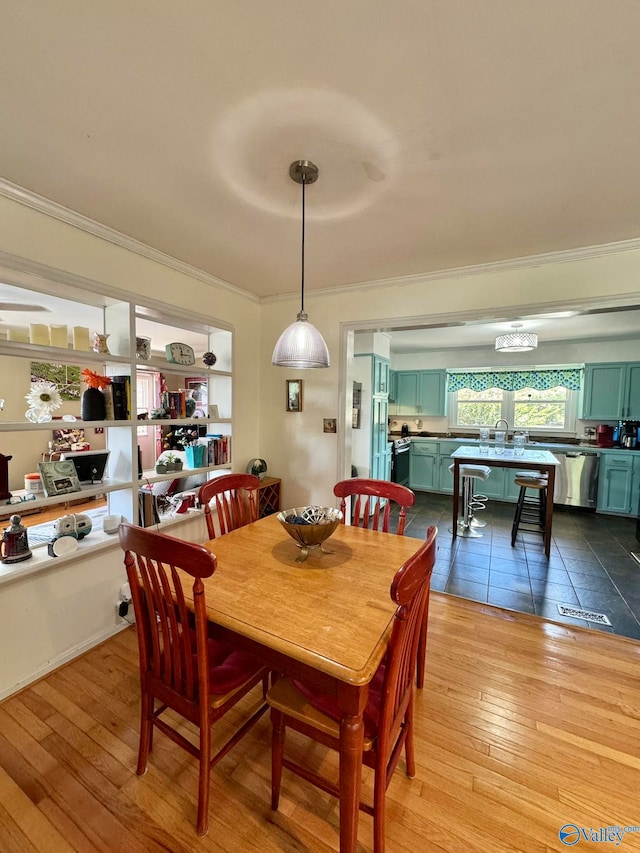 dining space with light wood-type flooring, sink, and crown molding