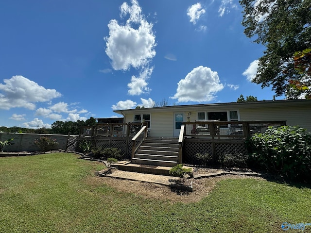 rear view of property featuring a wooden deck and a lawn