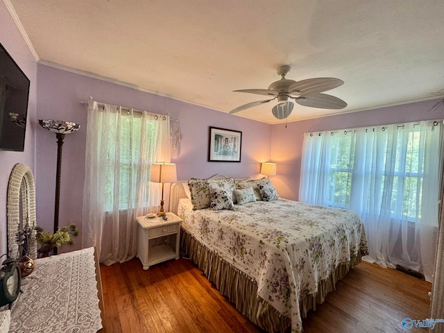 bedroom with ceiling fan, multiple windows, ornamental molding, and wood-type flooring