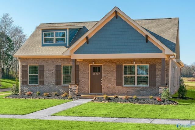 view of front of property with a front yard, covered porch, and brick siding