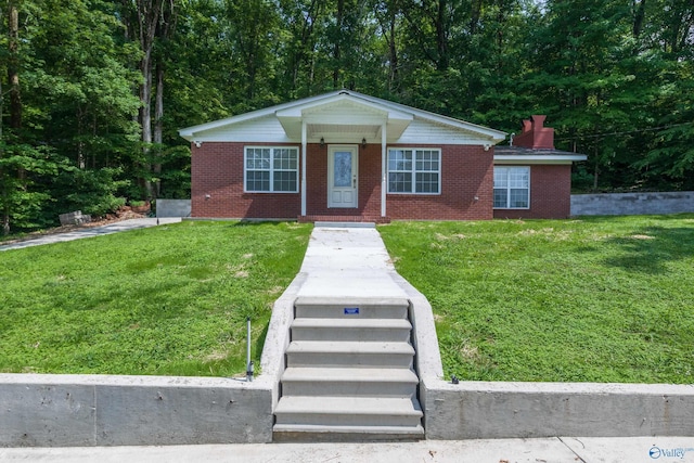 view of front of property with a front yard, brick siding, and a chimney