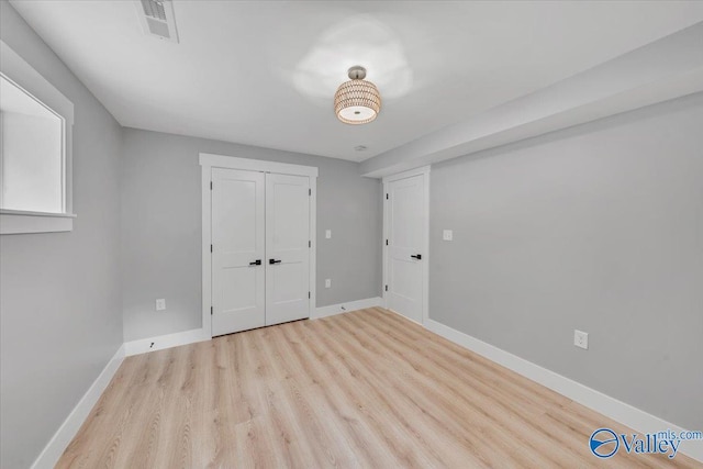 unfurnished bedroom featuring a closet, visible vents, light wood-style flooring, and baseboards