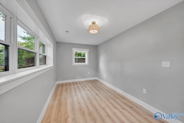 unfurnished room featuring visible vents, light wood-style flooring, and baseboards