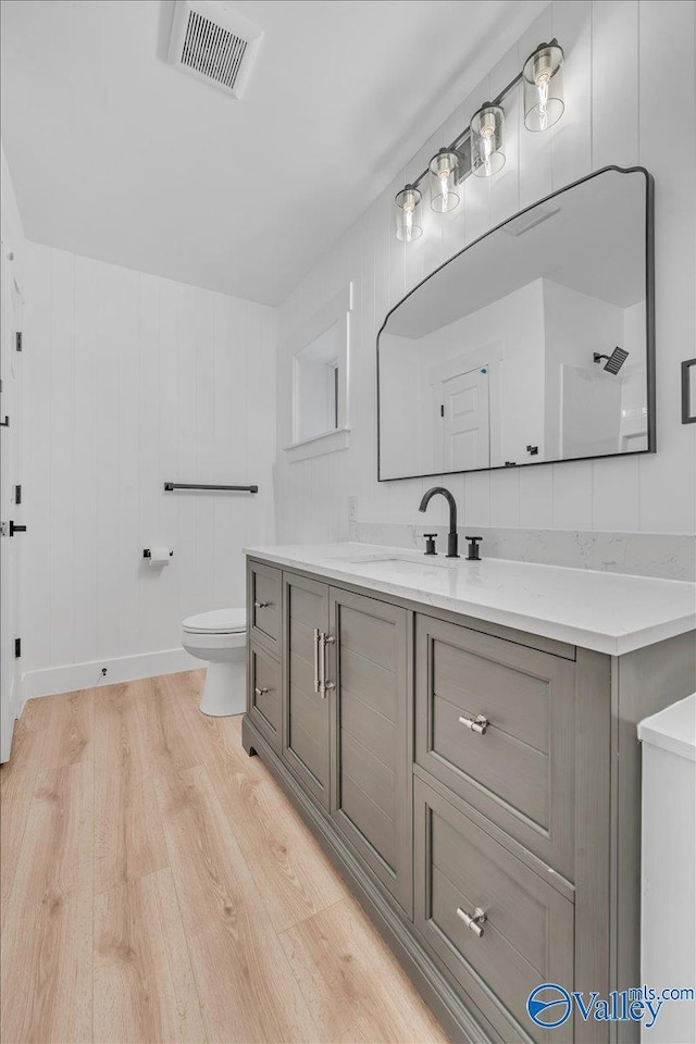 bathroom featuring toilet, visible vents, wood finished floors, and vanity