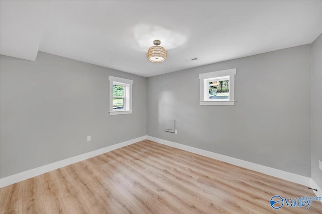 spare room with visible vents, light wood finished floors, and baseboards