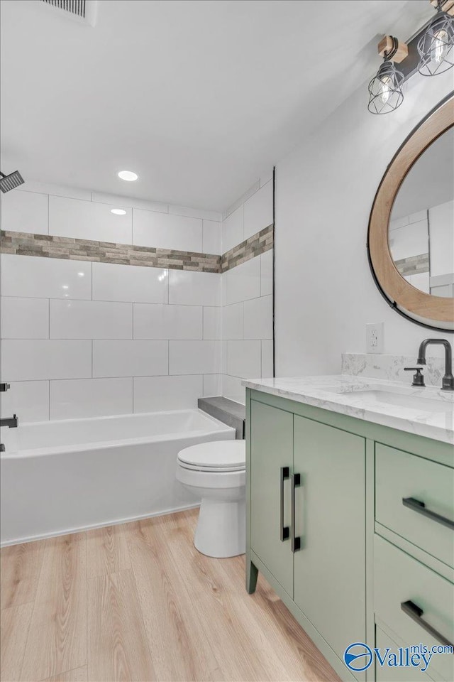 full bath with shower / washtub combination, vanity, toilet, and wood finished floors