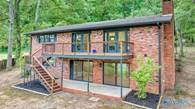 rear view of property featuring a patio area, a chimney, stairway, and brick siding