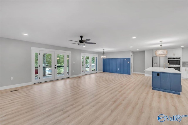 unfurnished living room featuring light wood-type flooring, recessed lighting, baseboards, and french doors