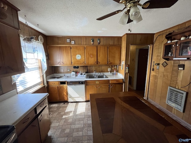 kitchen featuring a sink, heating unit, wooden walls, brown cabinetry, and white dishwasher