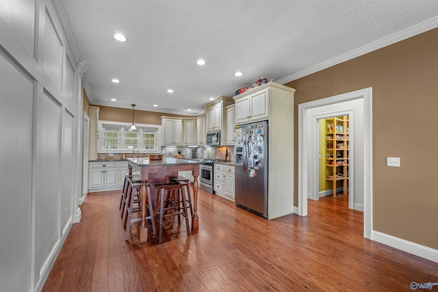 1635 County Road 47, Fyffe, AL 35971 - kitchen featuring stainless steel appliances, crown molding, a breakfast bar, decorative backsplash, and wood finished floors