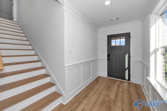 entrance foyer with crown molding and light hardwood / wood-style floors