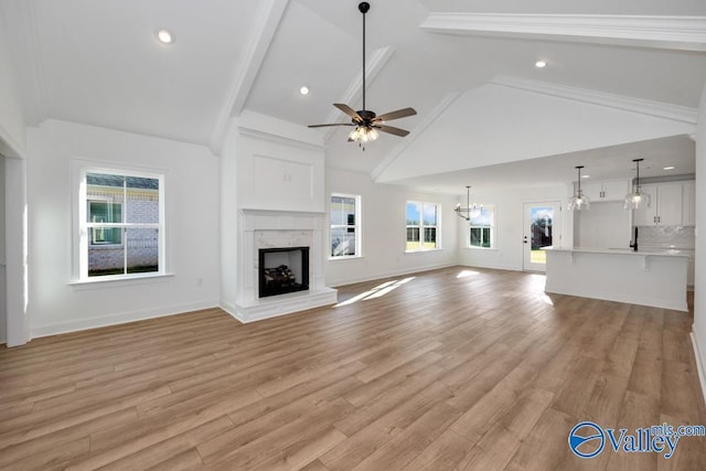 unfurnished living room featuring high vaulted ceiling, ceiling fan with notable chandelier, light hardwood / wood-style floors, and a premium fireplace