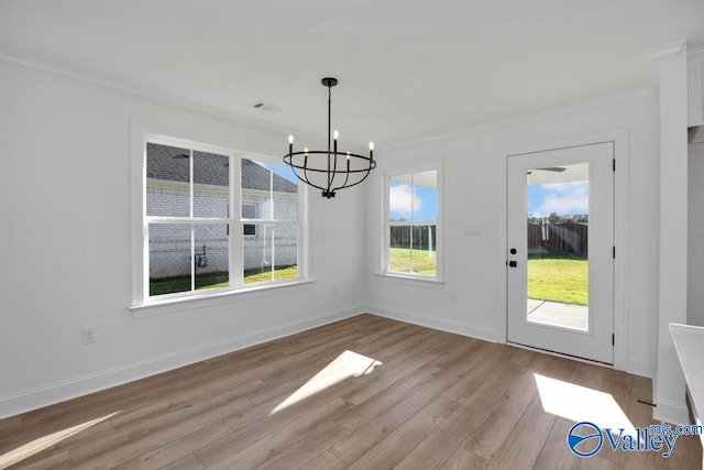 unfurnished dining area with ornamental molding, a notable chandelier, and light hardwood / wood-style flooring