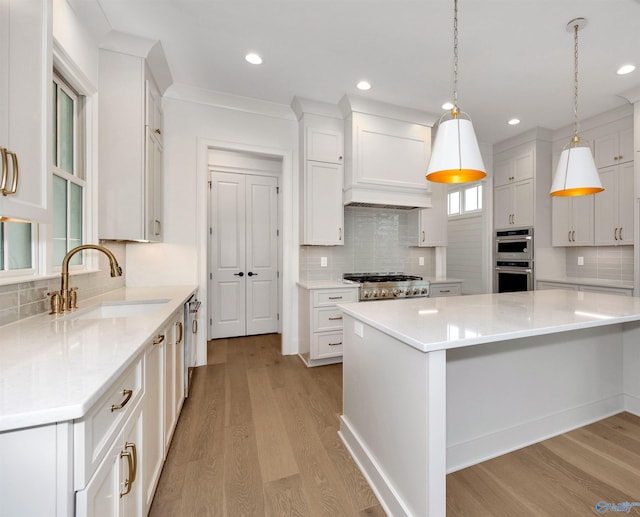 kitchen featuring white cabinets, decorative light fixtures, light hardwood / wood-style floors, and sink