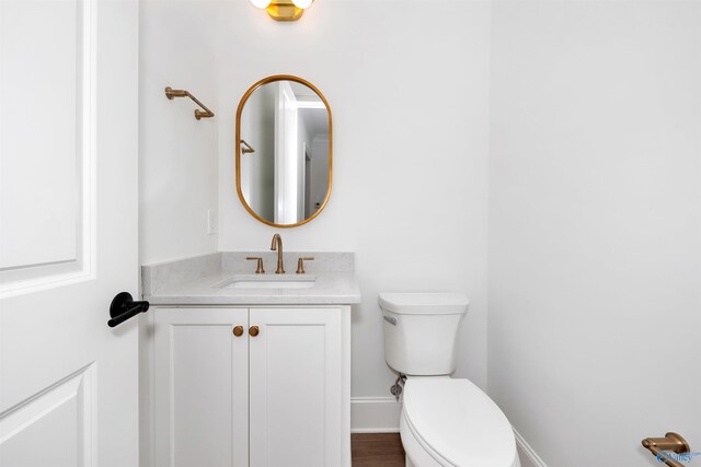 bathroom with wood-type flooring, vanity, and toilet