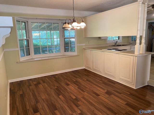 kitchen featuring a sink, visible vents, dark wood-style floors, baseboards, and hanging light fixtures