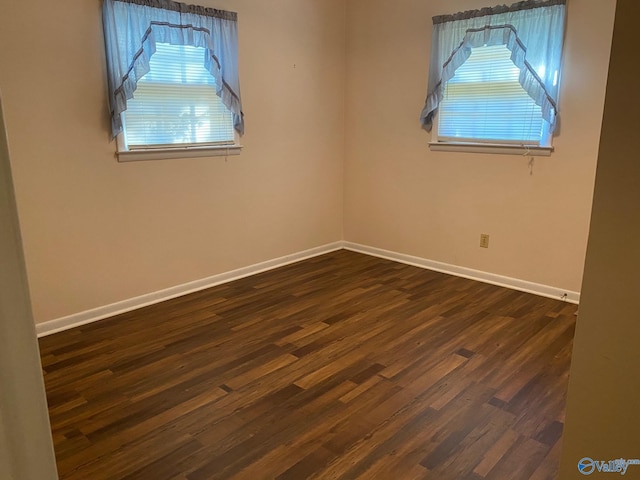 empty room featuring baseboards and dark wood-type flooring