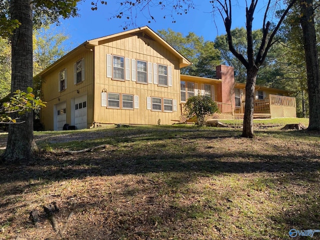 view of side of property with a wooden deck, a yard, and a garage