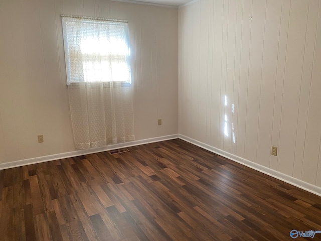 unfurnished room with dark wood-type flooring, wood walls, and ornamental molding