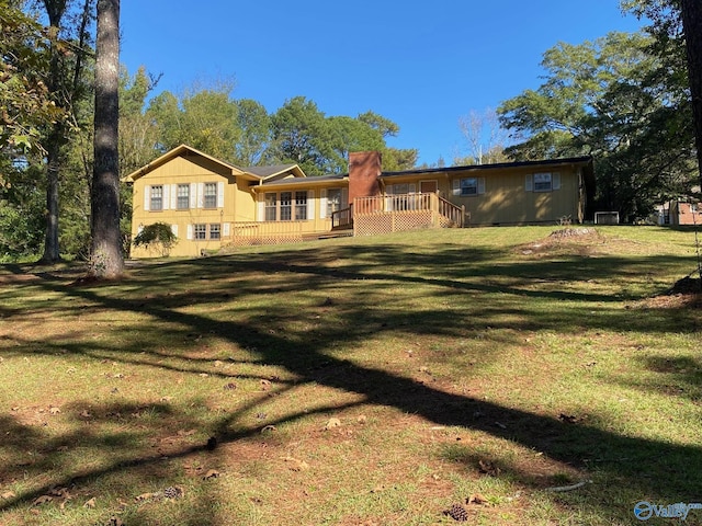 rear view of property with a wooden deck and a yard