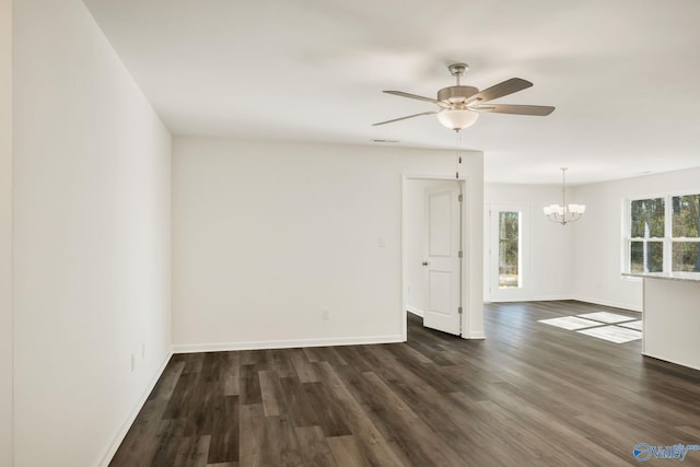 empty room with visible vents, ceiling fan with notable chandelier, baseboards, and dark wood-style flooring