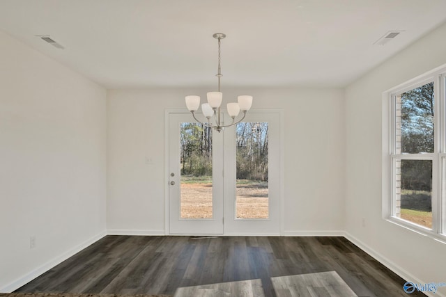 unfurnished dining area with an inviting chandelier, baseboards, visible vents, and dark wood-style flooring