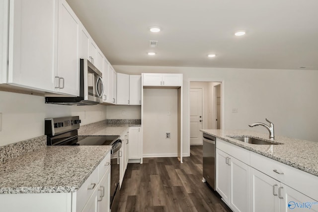 kitchen featuring light stone counters, dark wood-style flooring, a sink, appliances with stainless steel finishes, and white cabinetry