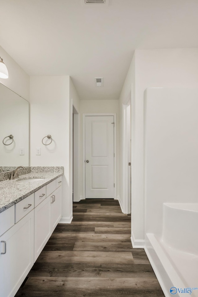 full bathroom with visible vents, vanity, baseboards, and wood finished floors