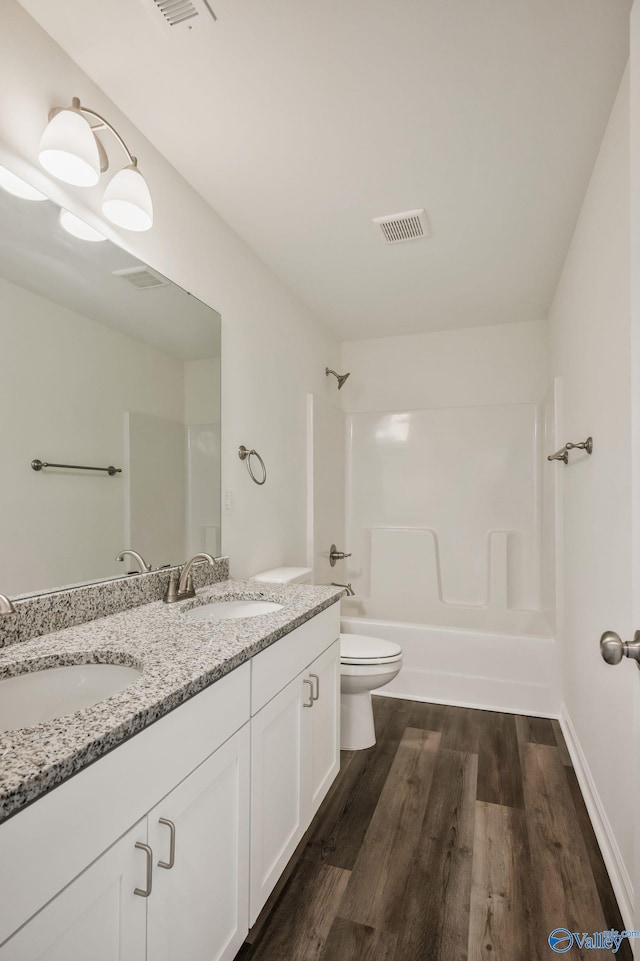 full bath featuring double vanity, shower / bath combination, wood finished floors, and a sink