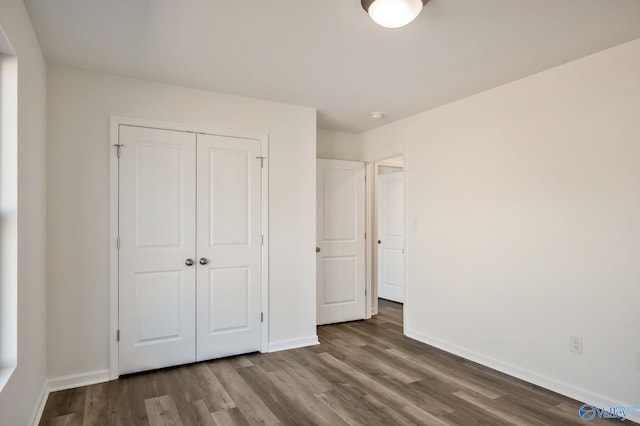 unfurnished bedroom with a closet, baseboards, and wood finished floors