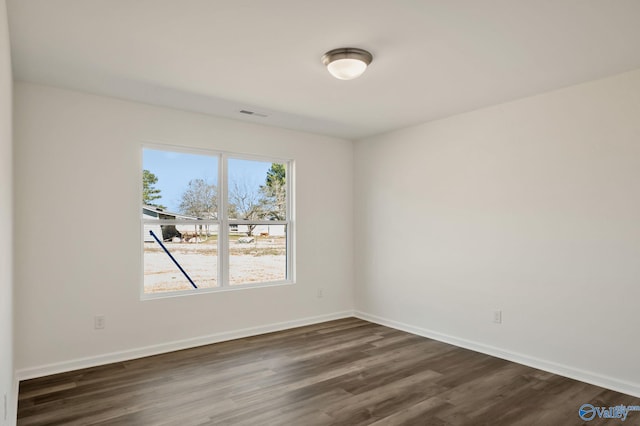 spare room featuring dark wood-style floors, visible vents, and baseboards