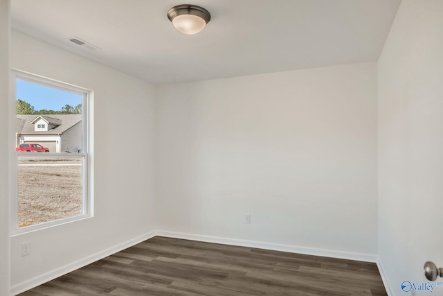 spare room with dark wood-type flooring, baseboards, and visible vents