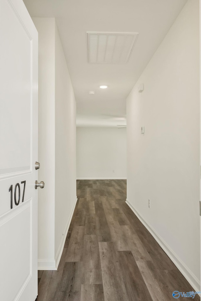 hallway featuring visible vents, baseboards, and wood finished floors