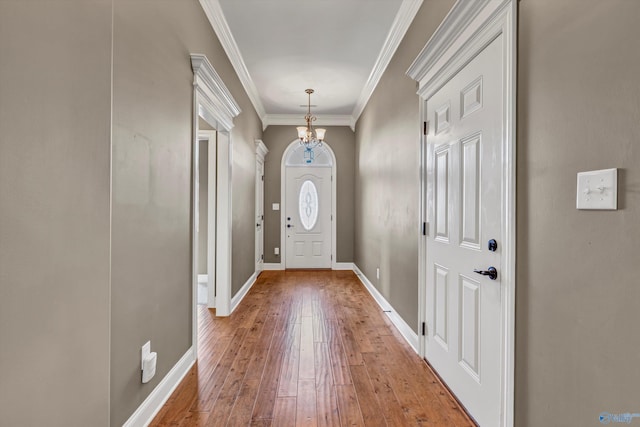 entryway featuring a notable chandelier, crown molding, and wood-type flooring