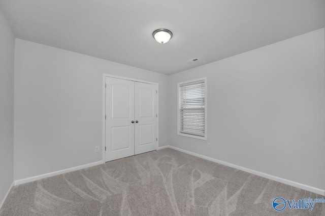 unfurnished bedroom featuring light carpet and a closet