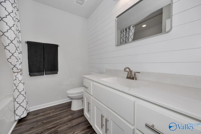 full bathroom with wooden walls, toilet, vanity, and hardwood / wood-style flooring