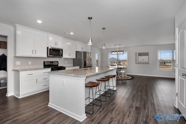 kitchen with white cabinetry, a kitchen island with sink, stainless steel appliances, and decorative light fixtures