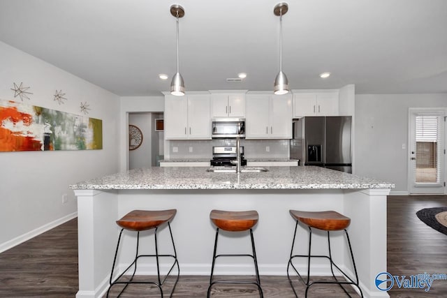 kitchen with white cabinets, decorative backsplash, light stone countertops, and appliances with stainless steel finishes