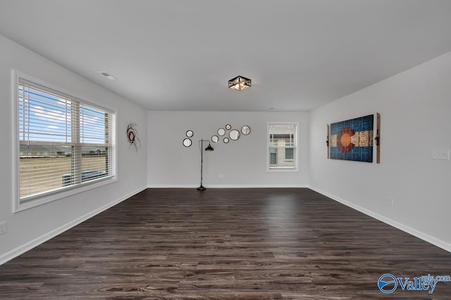 spare room featuring plenty of natural light and dark wood-type flooring