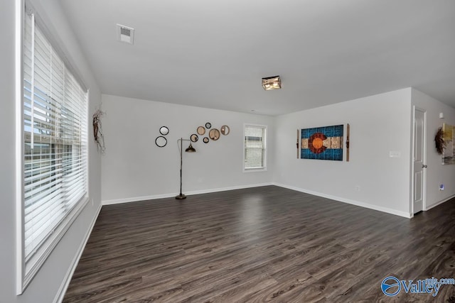 empty room with dark hardwood / wood-style flooring and a wealth of natural light