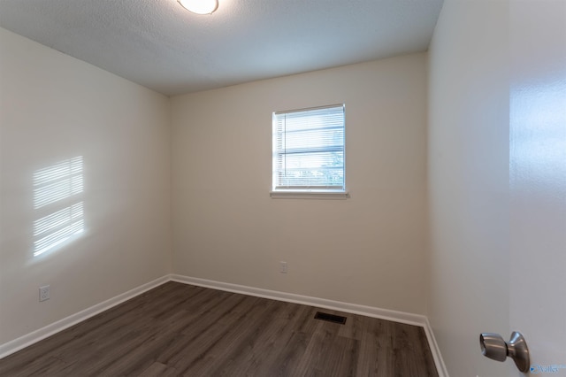 empty room with a textured ceiling and dark hardwood / wood-style floors