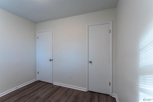 unfurnished bedroom with dark hardwood / wood-style floors and a textured ceiling