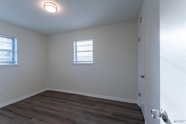 spare room featuring dark wood-type flooring and a textured ceiling