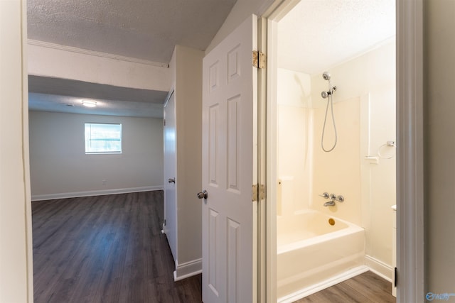 bathroom featuring a textured ceiling, hardwood / wood-style flooring, and shower / washtub combination