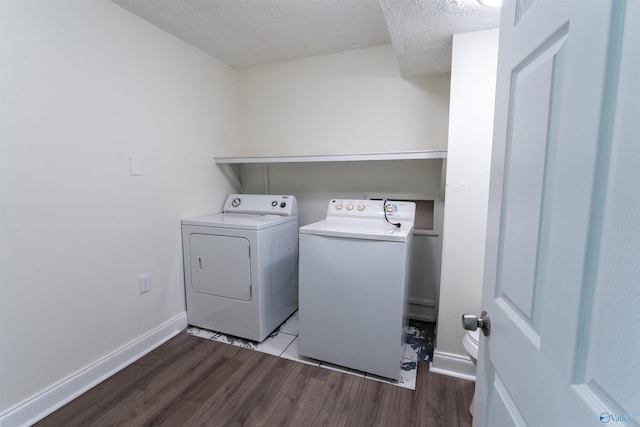 laundry area with a textured ceiling, separate washer and dryer, and dark wood-type flooring