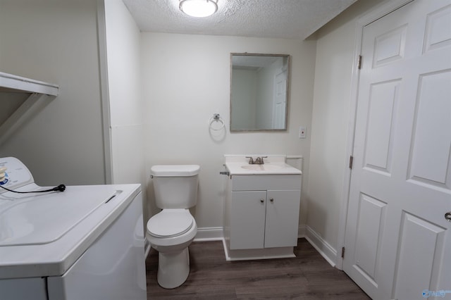 bathroom featuring a textured ceiling, washer / dryer, vanity, toilet, and hardwood / wood-style flooring