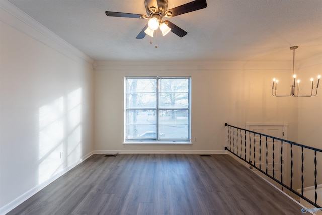 empty room with ceiling fan with notable chandelier, dark hardwood / wood-style flooring, and ornamental molding