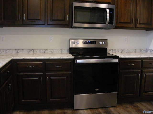 kitchen featuring dark brown cabinets, dark hardwood / wood-style floors, tile counters, and stainless steel appliances