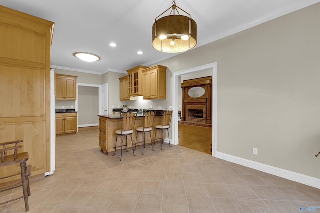 kitchen with a breakfast bar, hanging light fixtures, a fireplace, light tile patterned floors, and ornamental molding