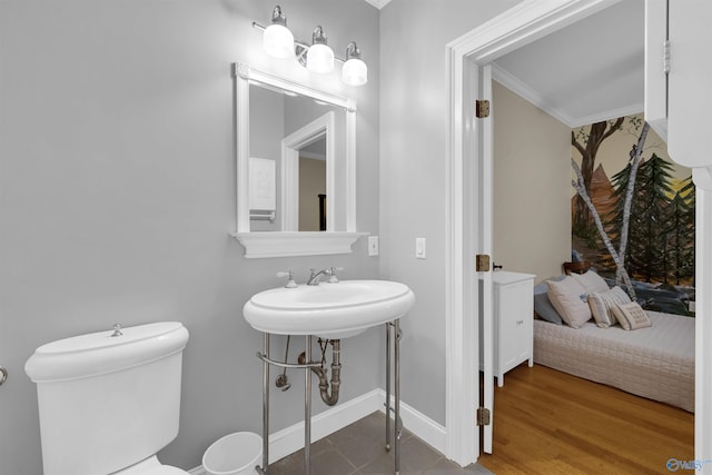 bathroom featuring wood-type flooring, toilet, ornamental molding, and sink